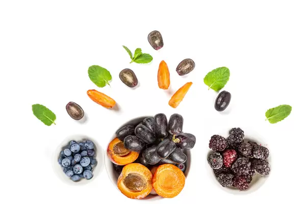 Ripe berries in bowls and on a white background with mint, top view