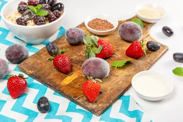 Ripe berries, mint leaves, sesame seeds and flax seeds with a bowl of oatmeal for breakfast