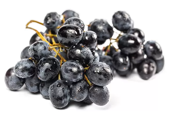 Ripe blue grapes with water drops on a white background