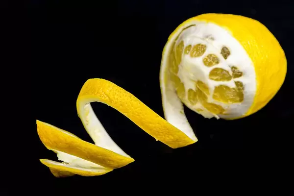 Ripe lemon with a spiral peel on a black background