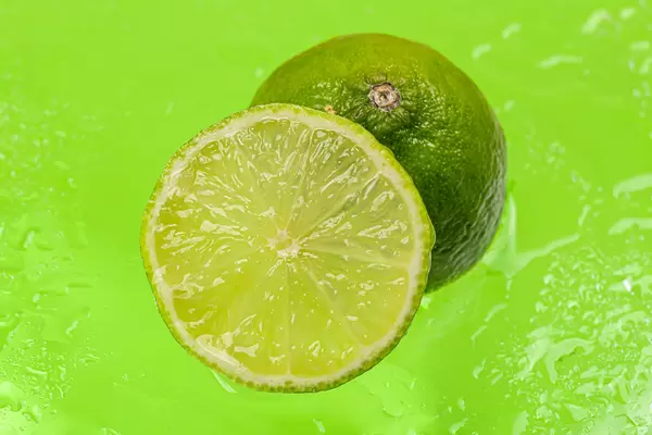 Ripe lime on a green background with water drops