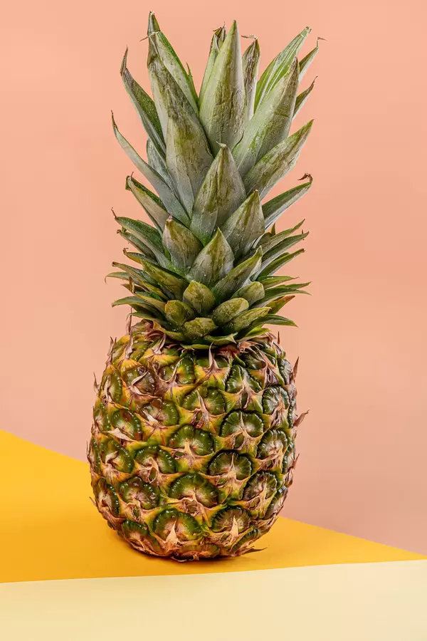 Ripe whole pineapple on yellow orange background