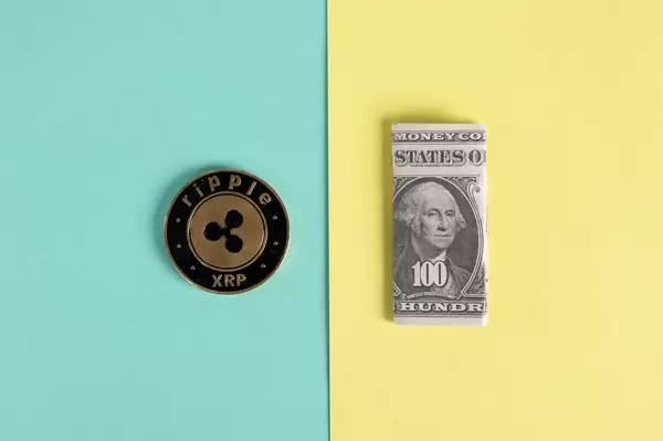 Ripple coin and folded one hundred dollar banknote