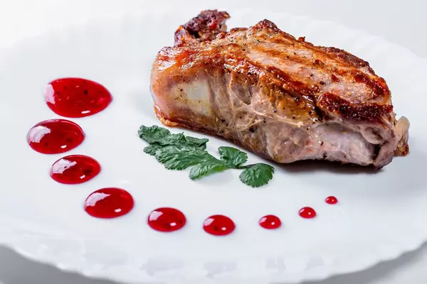 Roast meat with red sauce on a white plate