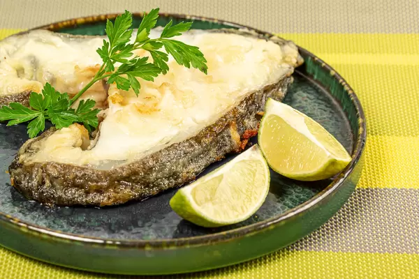Roasted catfish steak with parsley and lime slices, close up