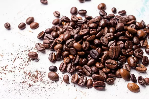 Roasted coffee beans lying loosely on a white surface