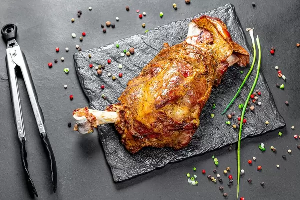 Roasted leg of young lamb with spices on black background
