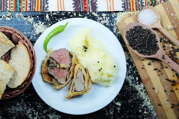 Roasted pork neck with mashed potatoes served with white bread. Black background (Flip 2019)