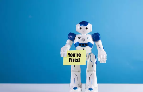 Robot holding a sing with You're fired text
