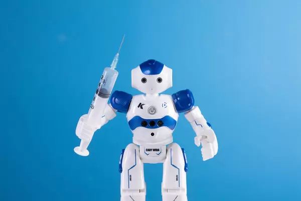 Robot holding syringe on blue background