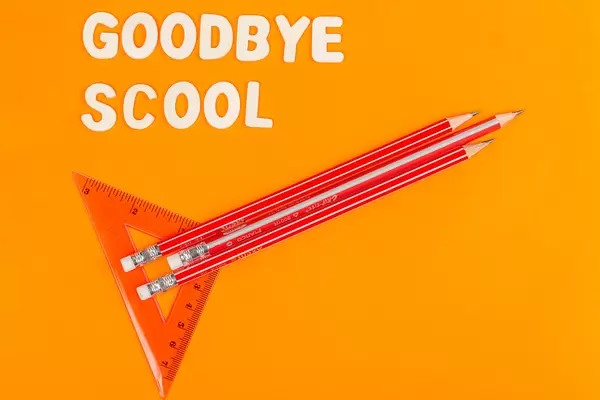 Rocket with pencils and ruler on orange background, goodbye school concept