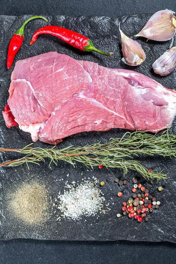 Rohes Fleisch, neben bunten Gewürzen, Knoblauch und Chili