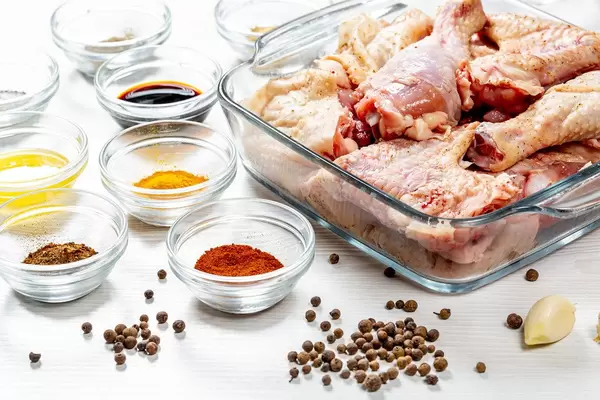 Rohes Hähnchen mit Gewürzen auf einem weißen Holztisch