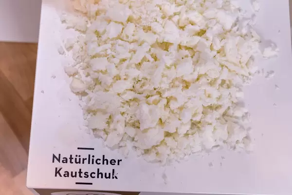 Rohstoff natürlicher Kautschuk für Reifen von ökologischem Holzfahrrad auf weißem Tisch