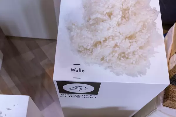 Rohstoff Wolle für Verarbeitung bei Produktion von ökologischem Holzfahrrad auf weißem Tisch