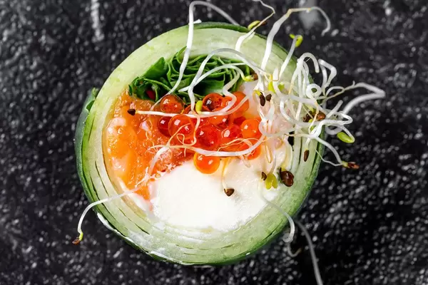 Roll with cucumber, salmon, cheese, arugula, micro greenery and red caviar on a black background. Top view (Flip 2019)