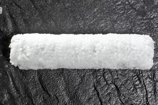 Roll with rice, cucumber and Philadelphia cheese on a black stone tray. Top view