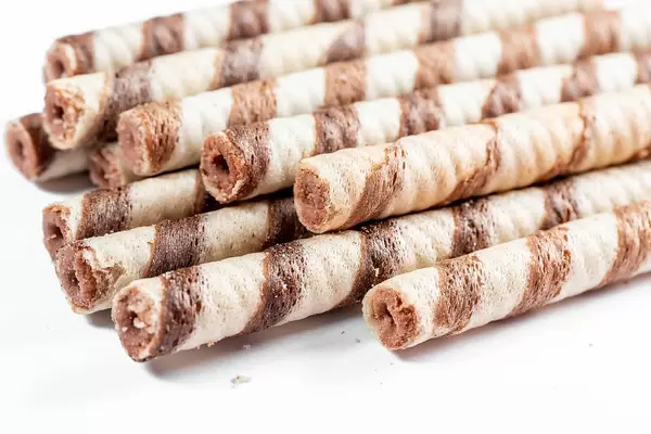 Rolled wafer filled with chocolate fudge on white background