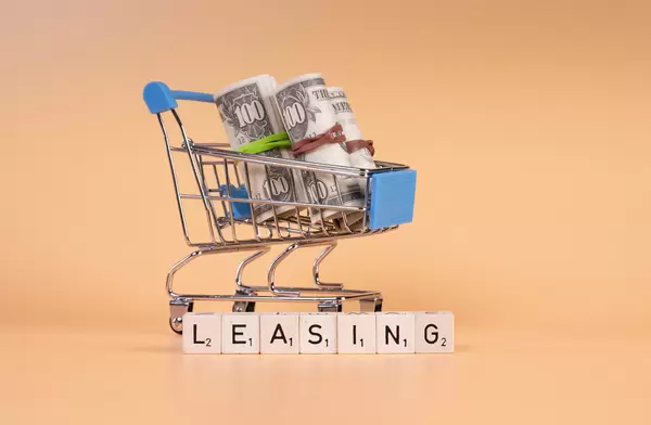 Rolls of dollar banknotes in shopping cart with Leasing text