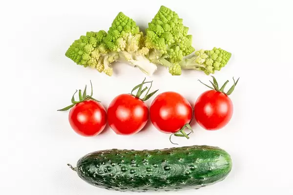 Romanesco, tomatoes and cucumber on a white background, top view