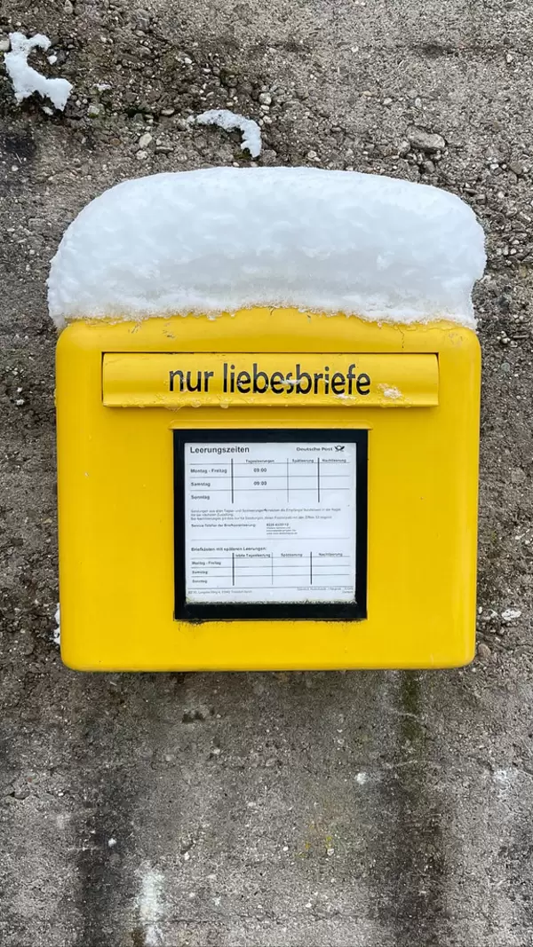 Romanticism: yellow letterbox of Deutsche Post with a sticker "Only love letters" in German and a layer of snow