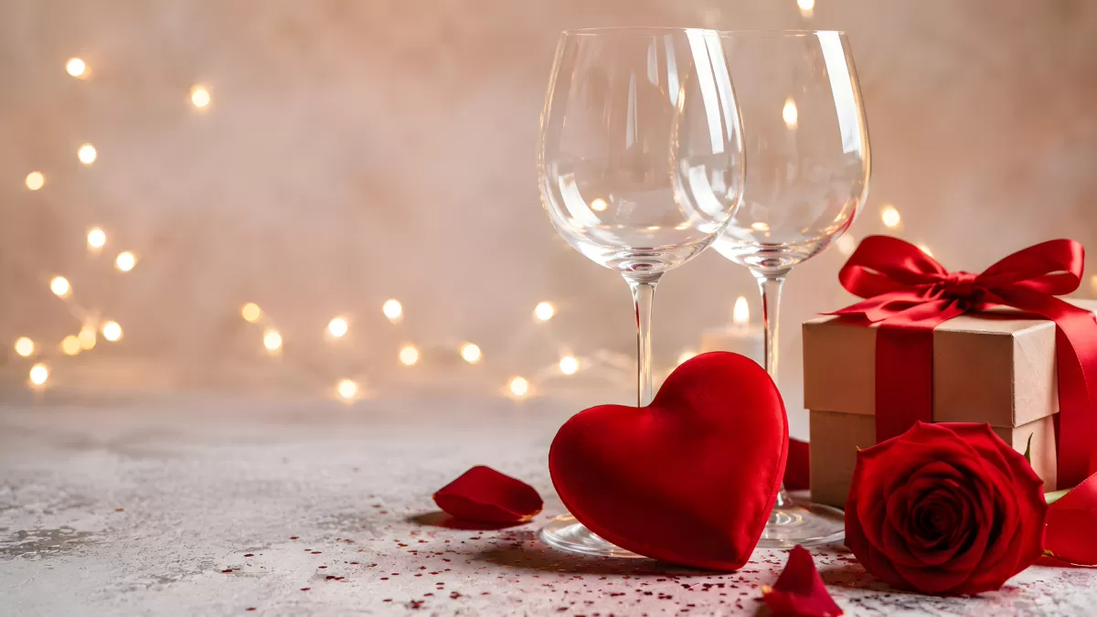 Romantisches Valentinstag-Arrangement mit Rosen und Weingläsern