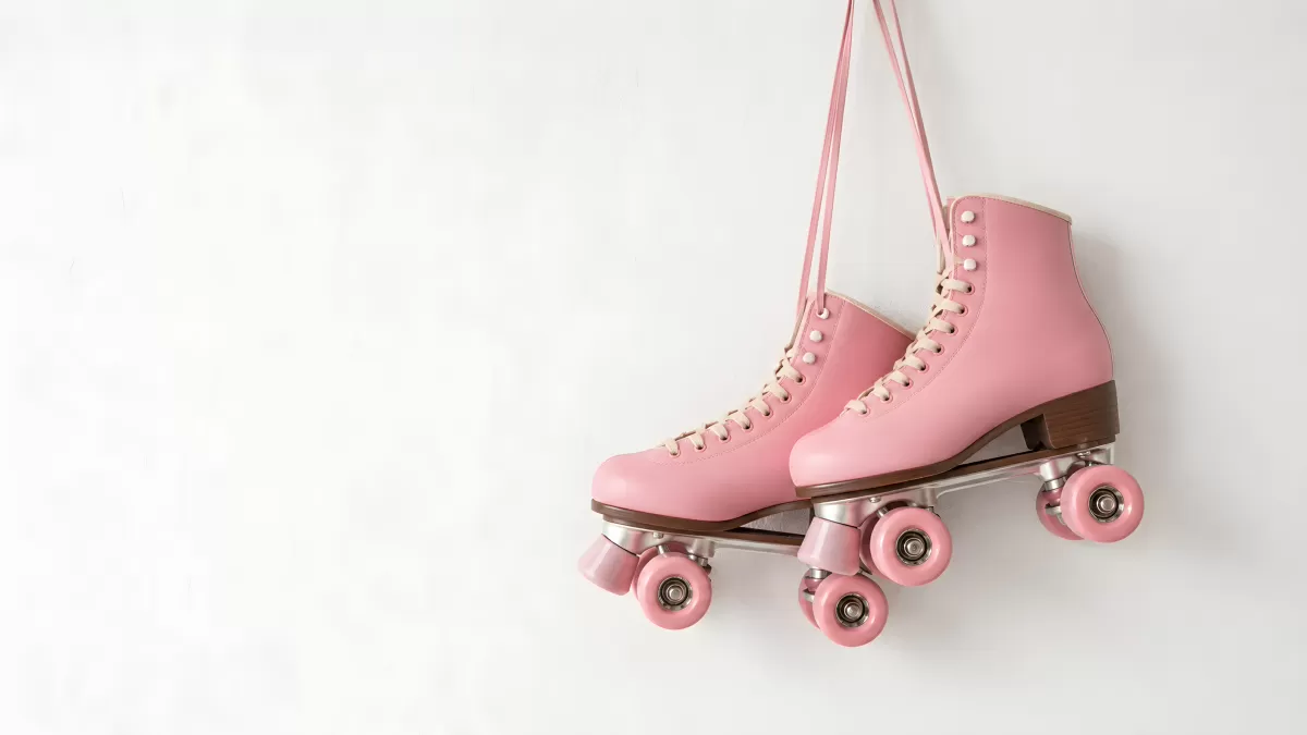 Rosa Rollschuhe hängen vor weißer Wand