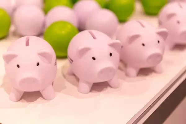 Rosafarbene Sparschweinchen und Bälle im Hintergrund