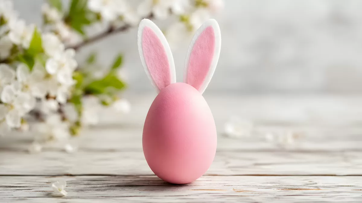 Rosafarbenes Osterei mit Hasenohren auf Holztisch