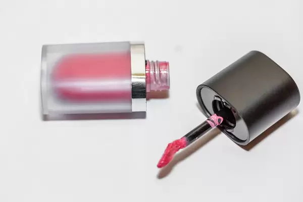 Rosaroter Lipgloss für frische Lippenfarbe liegt geöffnet auf weißem Tisch