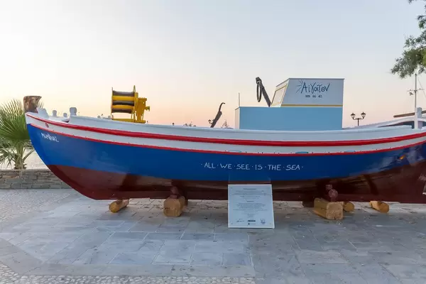 Rot-blau-weißes Fischerboot an Hafenpromenade in der Stadt Naoussa auf der griechischen Insel Paros