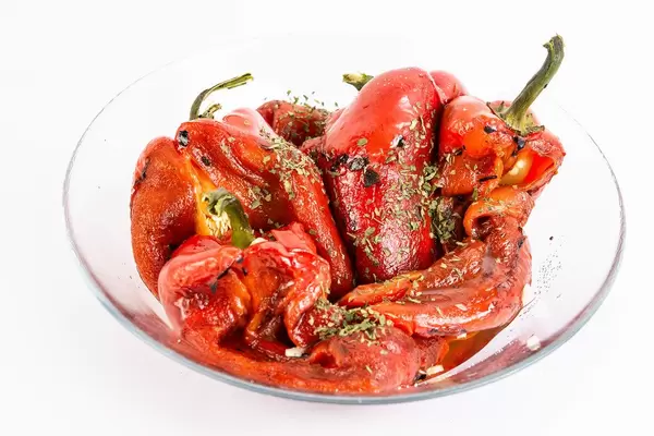 Rote gegrillte Paprika mit Kräutern in einer Glasschale