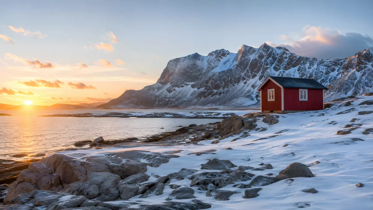 Rote Hütte an schneebedeckter Küste beim Sonnenuntergang