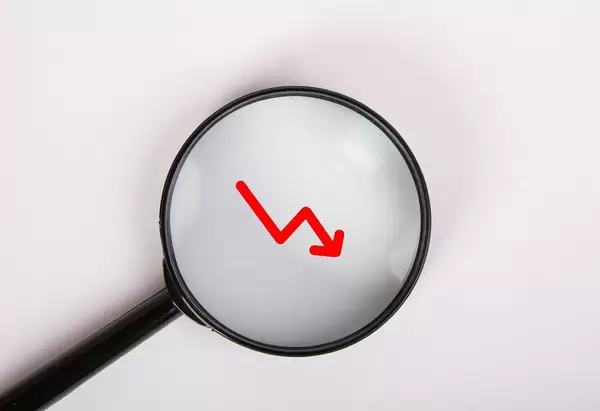 Rote Pfeilgrafik zeigt abwärts, vergrößert dargestellt unter einer Lupe