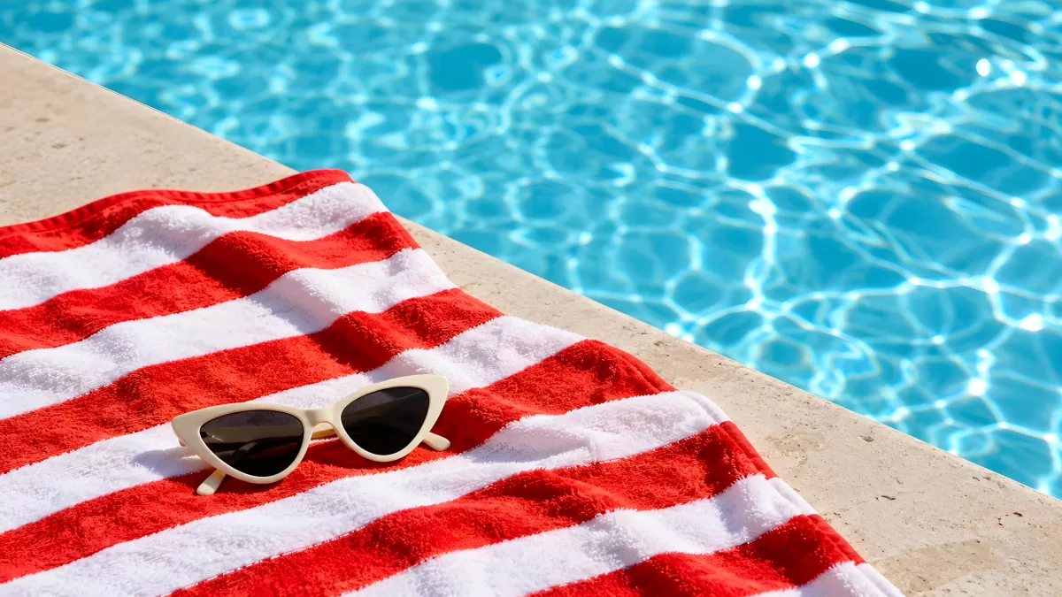 Rote Strandtücher und Sonnenbrille am Pool im Sommer