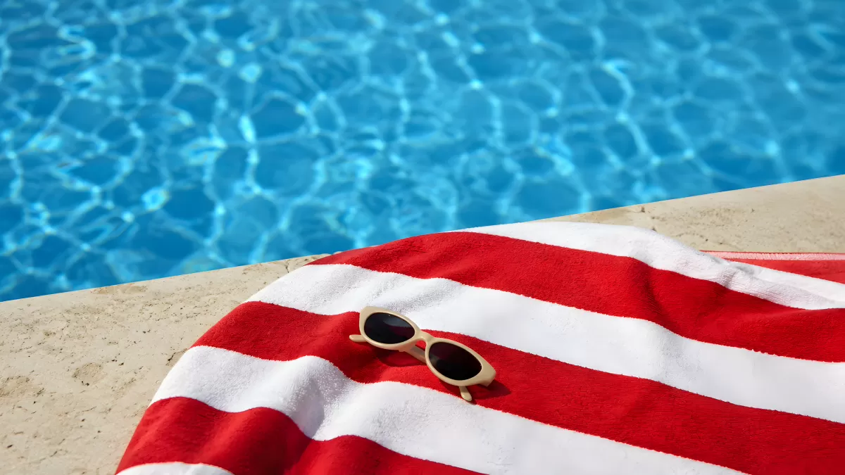 Rote Strandtücher und Sonnenbrille am Poolrand