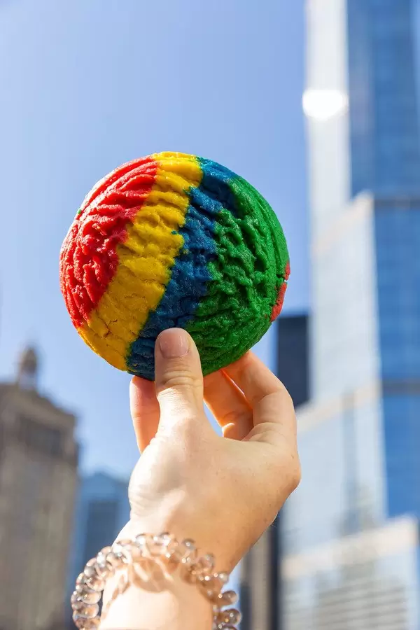 Roter-gelber-blauer-grüner Keks in der Hand mit Wolkenkratzern im Hintergrund