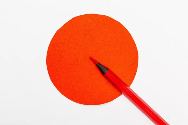 Roter Holzmalstift zeigt in einen roten Kreismittelpunkt als Symbol für genaue Entscheidungsfindung