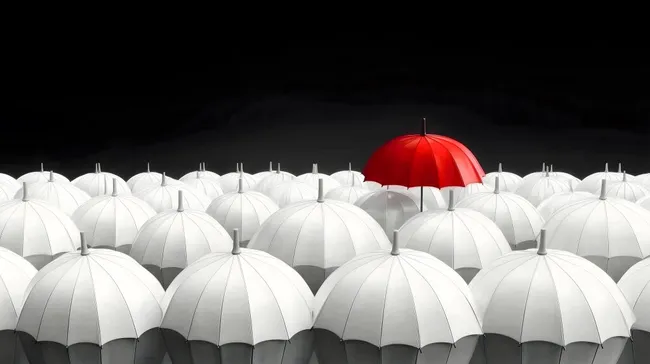 Roter Regenschirm hebt sich aus weißer Menge hervor