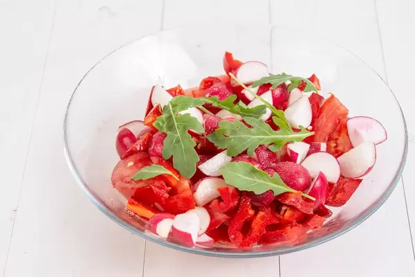 Roter Salat mit Tomate und Radieschen verfeinert mit Käse und Rucola in Schale