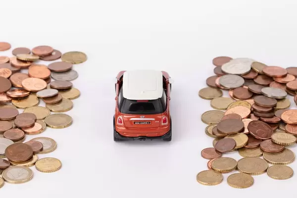 Rotes Auto fährt auf einer Straße aus Münzen