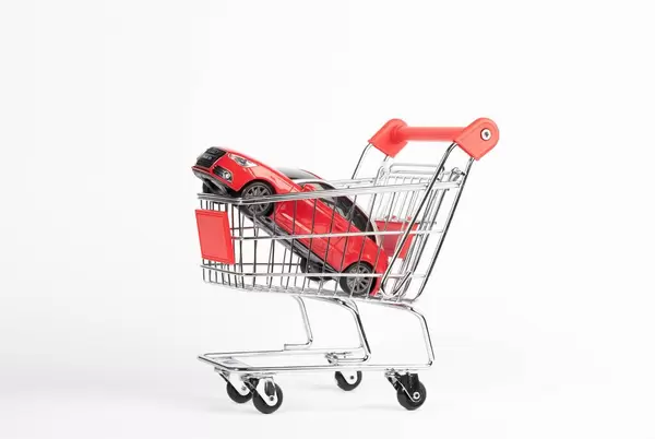 Rotes Auto in Einkaufswagen symbolisiert Anschaffung eines Fahrzeugs