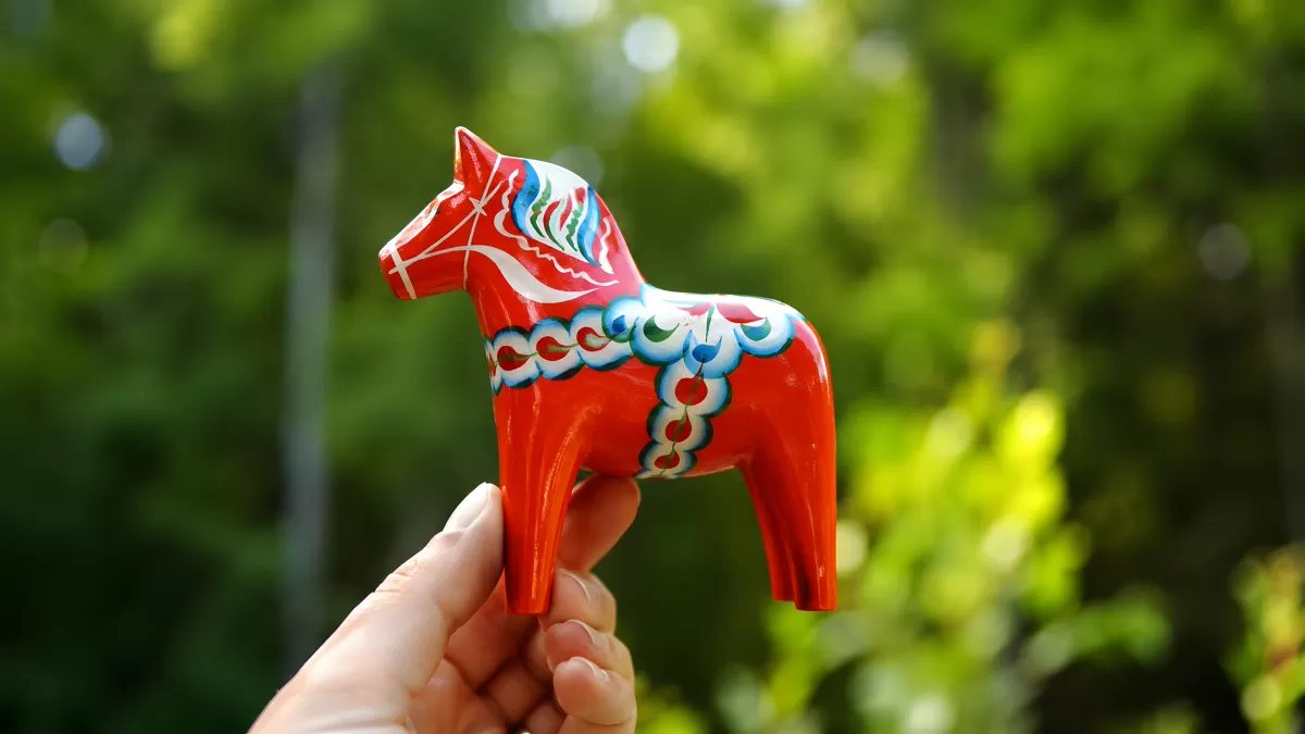 Rotes Dala-Pferd aus Holz zu Midsommar in der Hand gehalten