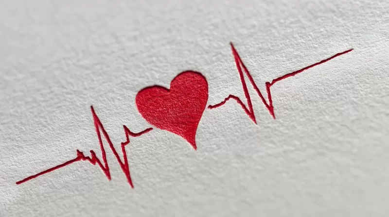 Rotes geprägtes Herz mit EKG Linie auf strukturiertem Papier