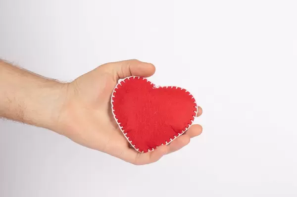 Rotes Herz in einer Hand, vor weißem Hintergrund