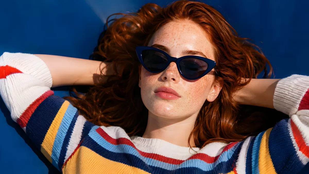 Rothaarige Frau mit Sonnenbrille liegt entspannt im Sommer