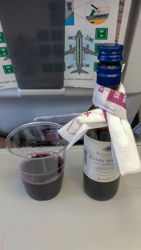 Rotwein wird mit Plastikbecher im Flugzeug auf der Flugreise als Drink serviert