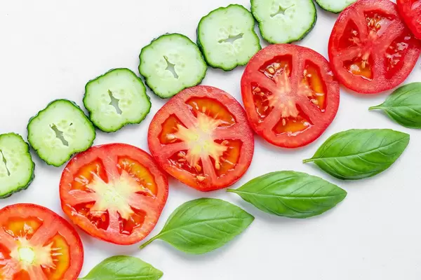 Round pieces of cucumber, tomato and Basil leaves. Top view