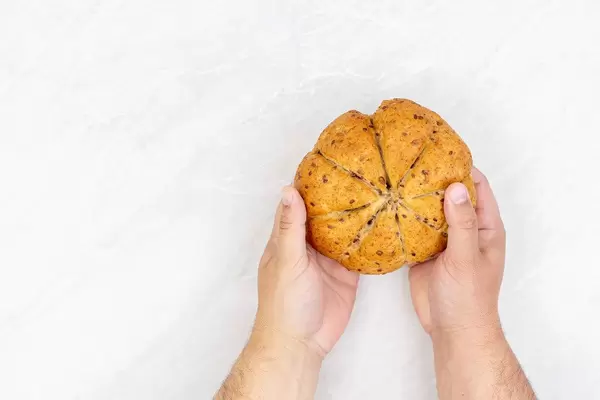Round whole wheat flour bread in the hand above table with copy space