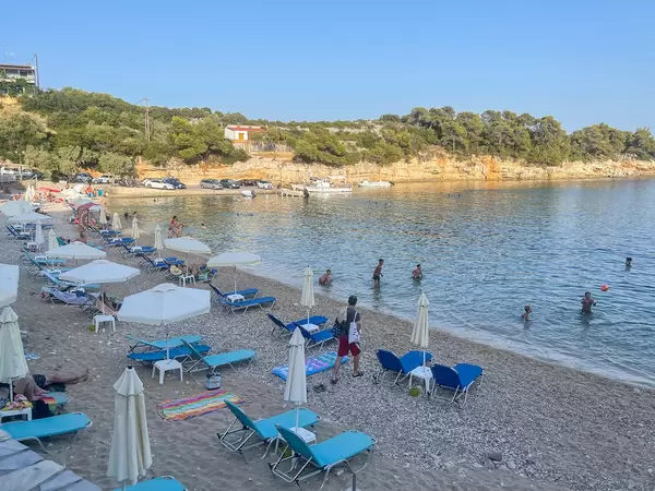 Rousoum Gialos beach in Patitiri on Greek island Alonnisos. Pebble beach with white parasols
